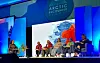 Panel of speakers seated on stage at the Arctic Encounter Summit in front of a large map screen.