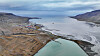 Luftfoto av Longyearbyen ved en arktisk fjord omgitt av fjell og tundra.
