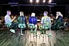 Fem paneldeltakere sitter på stoler på en scene foran publikum i en stor sal.