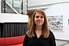 Kvinne i svart bluse står i et lyst, moderne interiør med kunst på veggene.