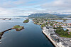 Flyfoto av Brønnøysund med Brønnøysundregistrenes bygg langs sjøen og fjellandskap i bakgrunnen.