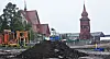 Mørk masse foran en rød trekirke, med lekeplass og byggearbeid i området.