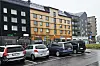 Regnvåt bygate med fargerike bygninger og parkerte biler.