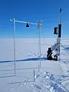 Måleutstyr og en feltarbeider på den snødekte Austfonna-isbreen.