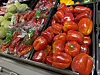 Stablede røde paprika i en grønnsaksdisk sammen med andre ferske grønnsaker.