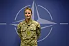 Mann i uniform står foran Nato-flagget.