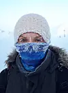 Person med snødekt lue og ansiktsmaske i et vinterlandskap